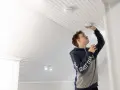 Ung man monterar en brandvarnare i taket. En viktig del av brandsäkerheten i hemmet.