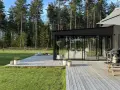 Modernt uterum med glaspartier och träaltan, perfekt för att bygga ett drömhem vid skogen.