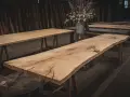 Råa ekbord med naturliga kanter, oljade och redo för utomhusbruk. En bukett blommor i en zinkhink står på ett av borden.