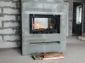 En nyinstallerad kamin med eld i. Byggarbetsplats med tegelväggar och golv.