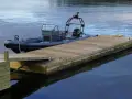 En grå RIB-båt ligger förtöjd vid en nybyggd flytbrygga i trä. Perfekt för att bygga flytbrygga och njuta av vattnet.