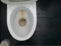 En smutsig toalett med kalkavlagringar. En pimpsten toalettborste står bredvid.