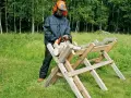 Man i skyddsutrustning använder motorsåg för att kapa ved på en sågbock. Ritning av en sådan konstruktion kan vara användbar.