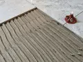 Läggning av klinker på betonggolv med fix. En del av golvet är täckt med fix, redo för nästa platta.