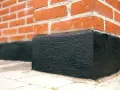 När man ska putsa sockel på ett tegelhus är det viktigt med ett bra skydd. Denna svarta, grova yta skyddar mot fukt.