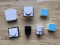 En samling Plejd-produkter, inklusive en vit Plejd-box, två dimmerknappar, två elkontakter och två styrenheter som stöder Plejd-protokoll.