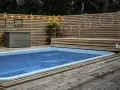 En avkopplande utomhusmiljö med pool och trädäck. En idé för att bygga eget pooltak kan inspireras av den snygga träpanelen och belysningen.