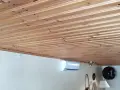 Ett vackert träpaneltak, redo att måla. En luftkonditionering och gitarrer syns nedanför.