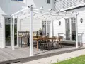 En vit pergola med tygtak skapar en mysig uteplats med matbord och stolar. Perfekt för att bygga pergola med plasttak för soliga dagar.