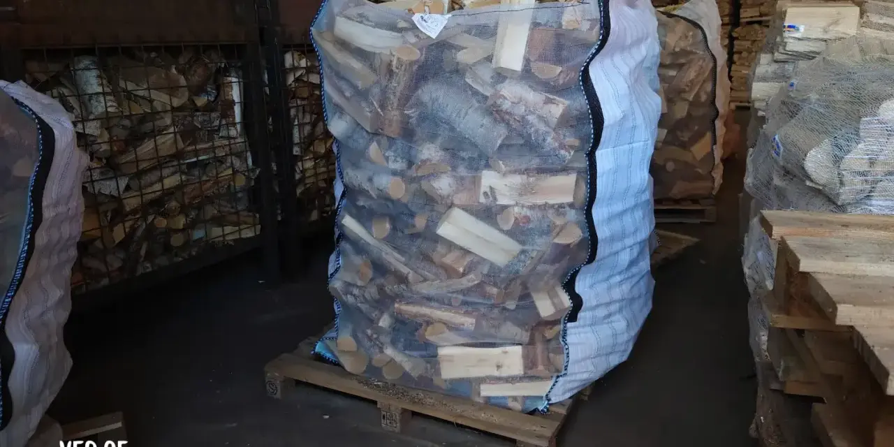 Stor säck med ved på pall, redo att stapla. Veden är kluven och förpackad för leverans.