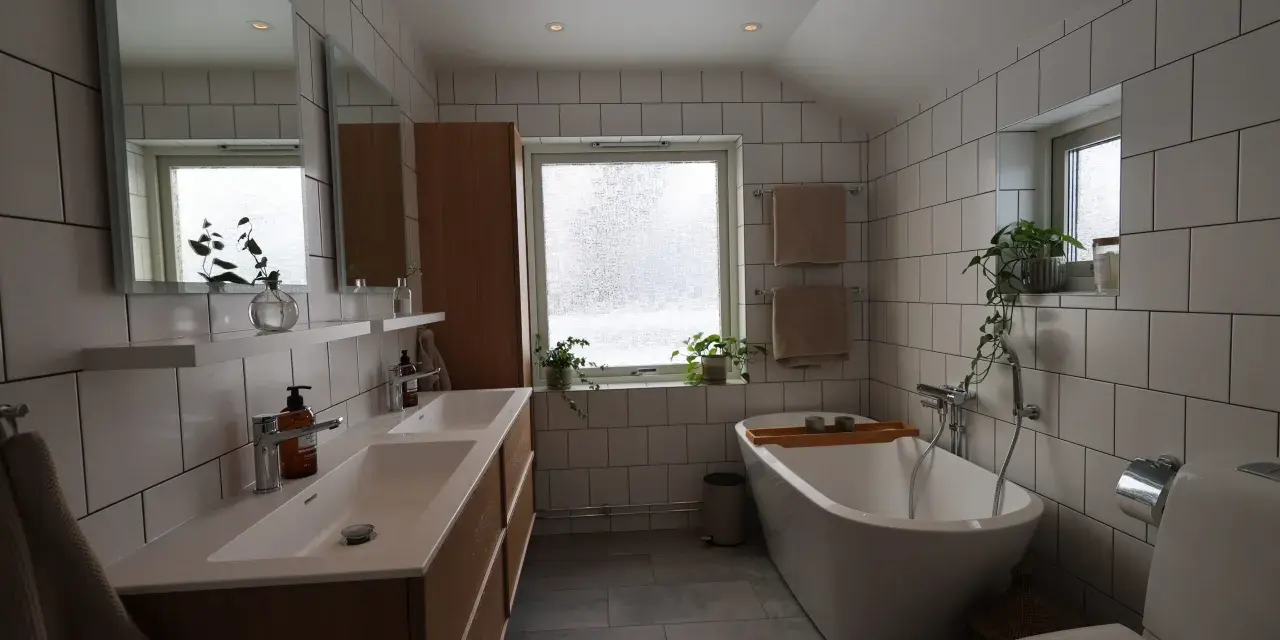 Modernt badrum med dubbla handfat, fristående badkar och vitt kakel. Perfekt för dig som vill renovera badrum.