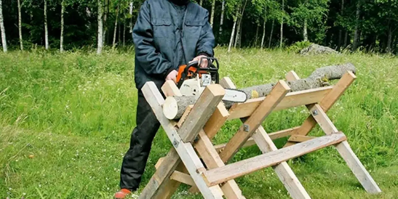 Man i skyddsutrustning använder motorsåg för att kapa ved på en sågbock. Ritning av en sådan konstruktion kan vara användbar.