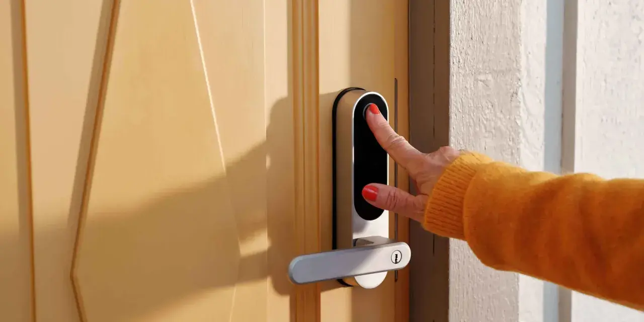 En hand med orange tröja använder fingeravtrycksläsaren på ett modernt dörrlås. Kanske ett nimly touch pro problem uppstod?