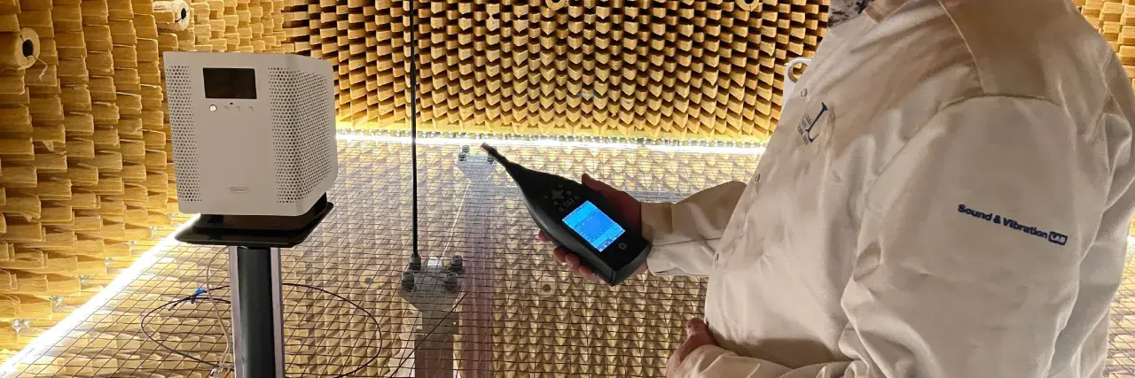 Person i laboratorierock mäter ljudnivån från en luftrenare utan filter i ett ekofritt rum.