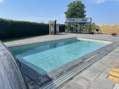 En vacker pool med mosaikdetaljer, perfekt för att bygga egen pool. Omgiven av en modern uteplats med växthus och dusch.