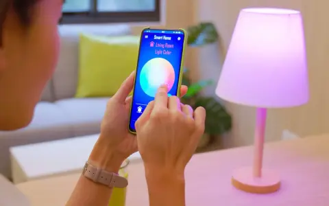 Person styr lampor med iPhone. Appen "Smart Home" visar färgval för vardagsrumsljuset.