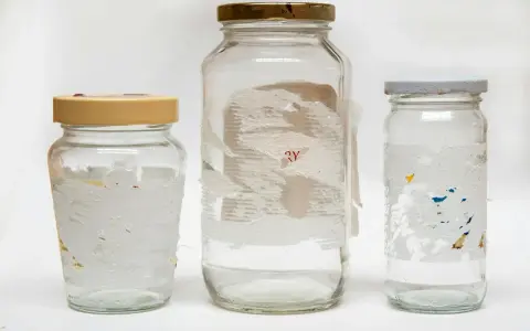 Tre glasburkar med rester av etiketter. Svårt att ta bort klister från glas, men dessa burkar visar hur det kan se ut.