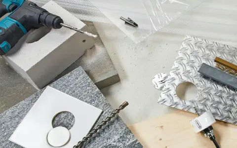 Borra i tegel med slagborr och olika borr. Material som granit, metall och trä ligger utspridda.