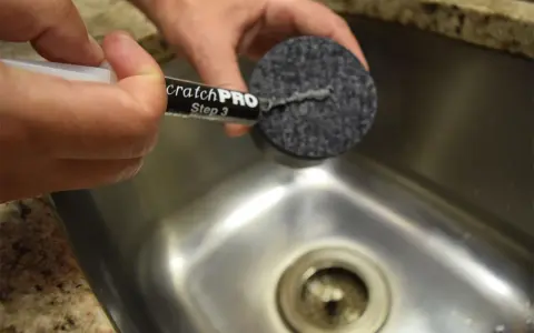 Händer använder en produkt för att ta bort repor på rostfritt stål.