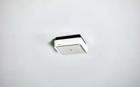 En vit och svart brandvarnare från Wiser monterad i taket. Denna brandvarnare utan batteri är redo att installeras.