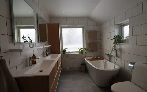 Modernt badrum med dubbla handfat, fristående badkar och vitt kakel. Perfekt för dig som vill renovera badrum.