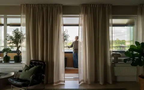 En person står vid balkongdörren och njuter av utsikten, redo att kyla ner sovrummet.
