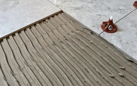 Läggning av klinker på betonggolv med fix. En del av golvet är täckt med fix, redo för nästa platta.