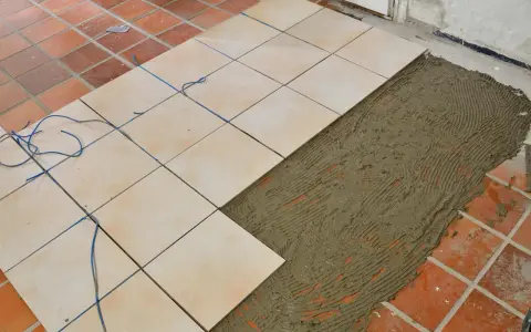Läggning av nya ljusa klinkerplattor ovanpå befintliga, med fogmassa redo för mer klinker på klinker.