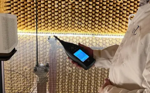 Person i laboratorierock mäter ljudnivån från en luftrenare utan filter i ett ekofritt rum.