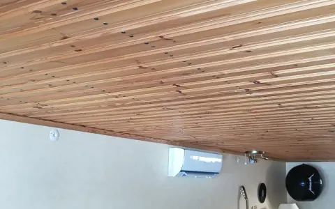 Ett vackert träpaneltak, redo att måla. En luftkonditionering och gitarrer syns nedanför.