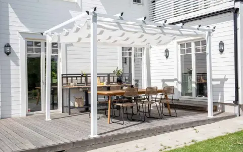 En vit pergola med tygtak skapar en mysig uteplats med matbord och stolar. Perfekt för att bygga pergola med plasttak för soliga dagar.