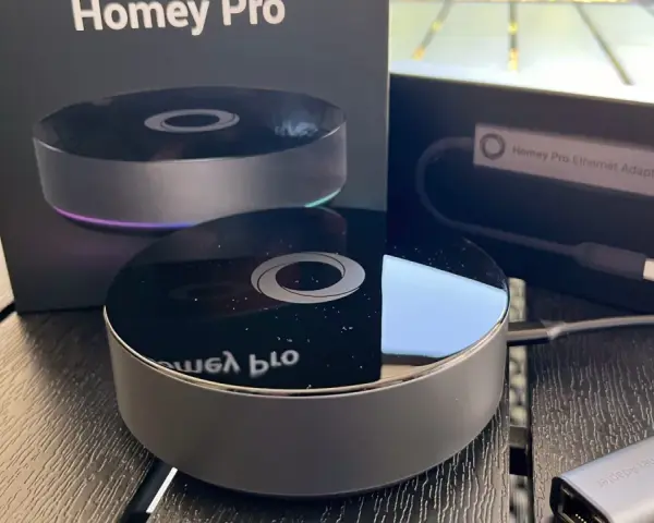 Homey Pro 2019 och Ethernet-adapter på ett träbord. En smart hem-hub för ett bekvämt hem.