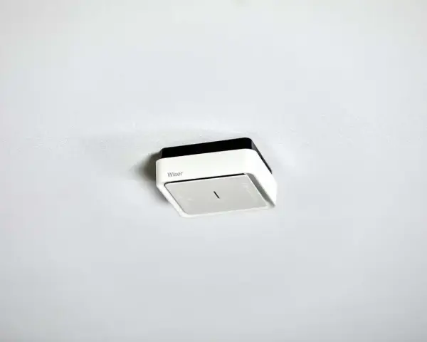 En vit och svart brandvarnare från Wiser monterad i taket. Denna brandvarnare utan batteri är redo att installeras.