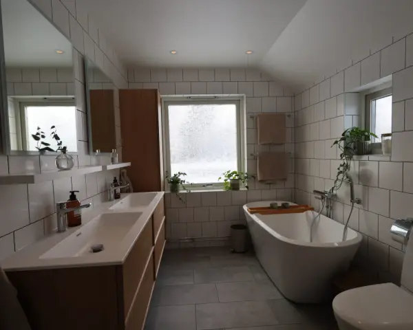 Modernt badrum med dubbla handfat, fristående badkar och vitt kakel. Perfekt för dig som vill renovera badrum.