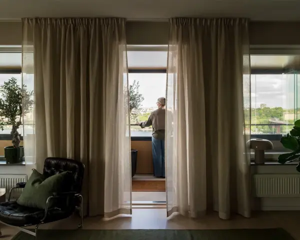 En person står vid balkongdörren och njuter av utsikten, redo att kyla ner sovrummet.