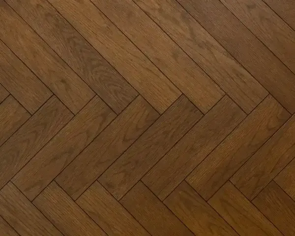 Vacker fiskbensparkett i mörkt trä, redo att slipa för att återfå sin glans.