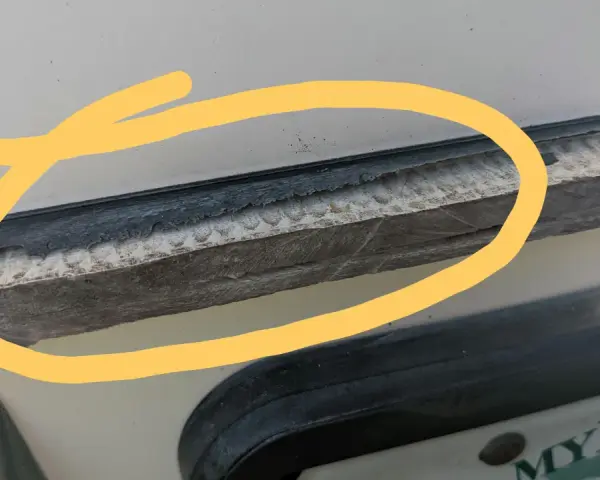 Detaljerad bild som visar hur man kan ta bort silikon med aceton. En gul cirkel markerar ett område med gammal silikon som behöver tas bort.