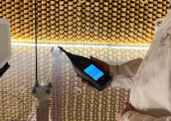 Person i laboratorierock mäter ljudnivån från en luftrenare utan filter i ett ekofritt rum.