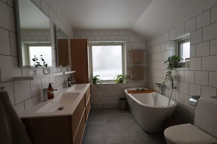 Modernt badrum med dubbla handfat, fristående badkar och vitt kakel. Perfekt för dig som vill renovera badrum.