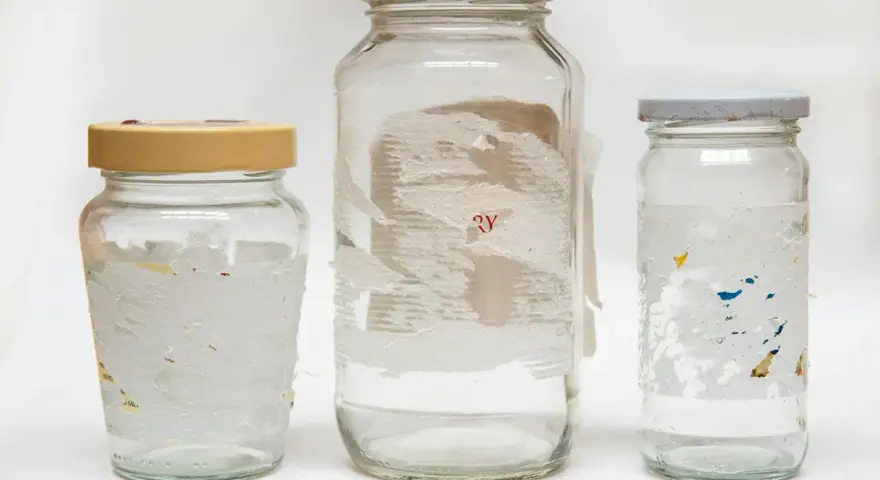 Tre glasburkar med rester av etiketter. Svårt att ta bort klister från glas, men dessa burkar visar hur det kan se ut.