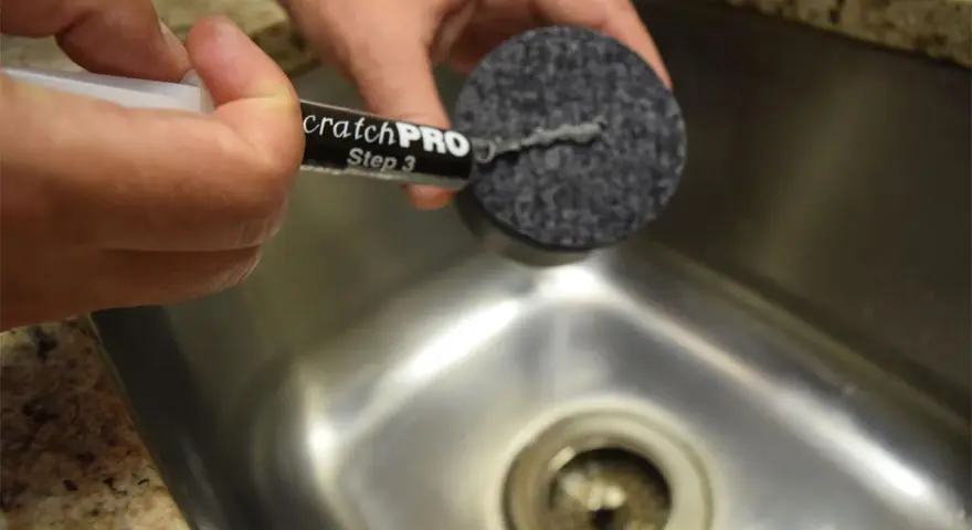 Händer använder en produkt för att ta bort repor på rostfritt stål.