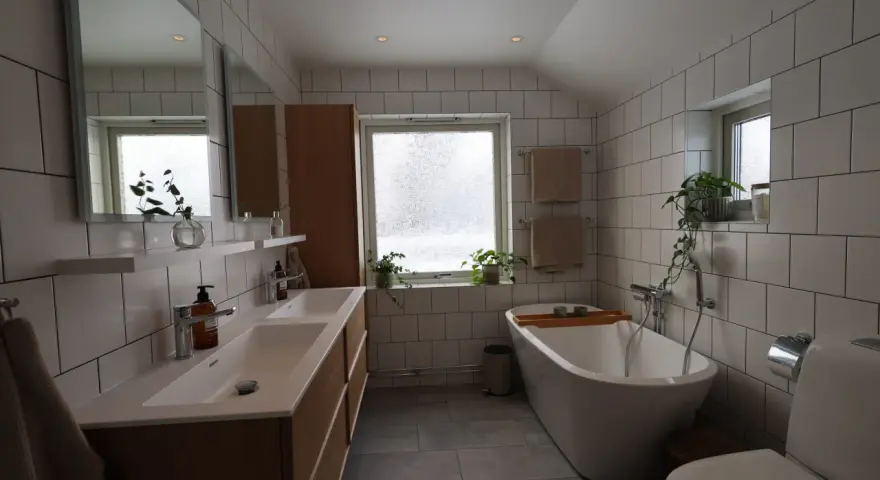 Modernt badrum med dubbla handfat, fristående badkar och vitt kakel. Perfekt för dig som vill renovera badrum.
