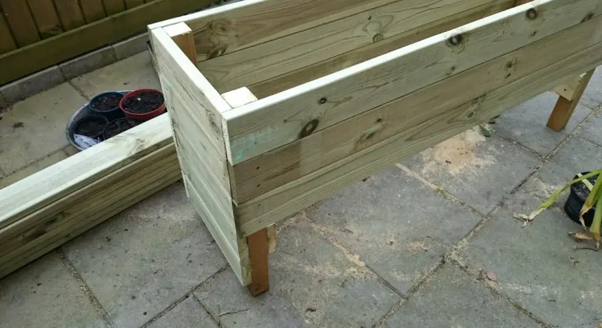 Påbörjat projekt att bygga blomlåda av tryckimpregnerat virke. Några krukor med jord står redo.