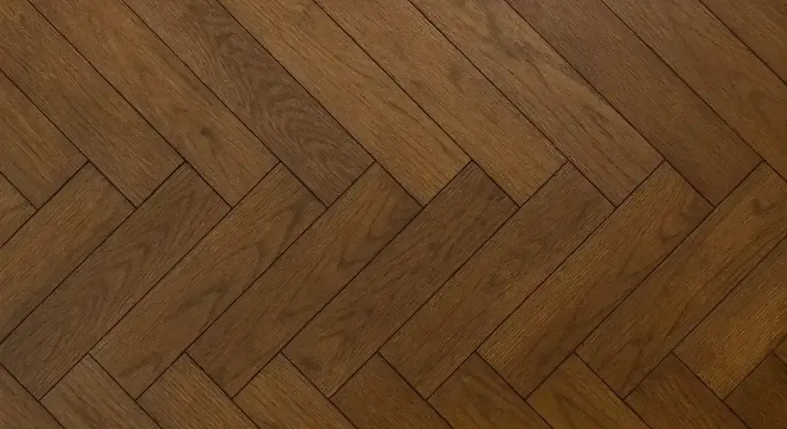 Vacker fiskbensparkett i mörkt trä, redo att slipa för att återfå sin glans.