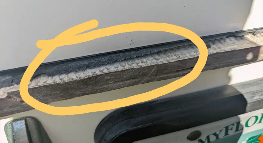 Detaljerad bild som visar hur man kan ta bort silikon med aceton. En gul cirkel markerar ett område med gammal silikon som behöver tas bort.
