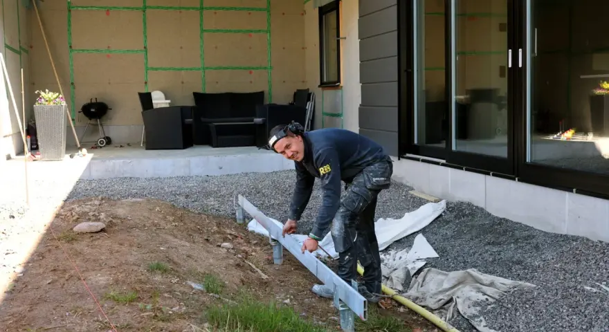 Bygger altan på mark. En man mäter upp stommen för en ny altan.