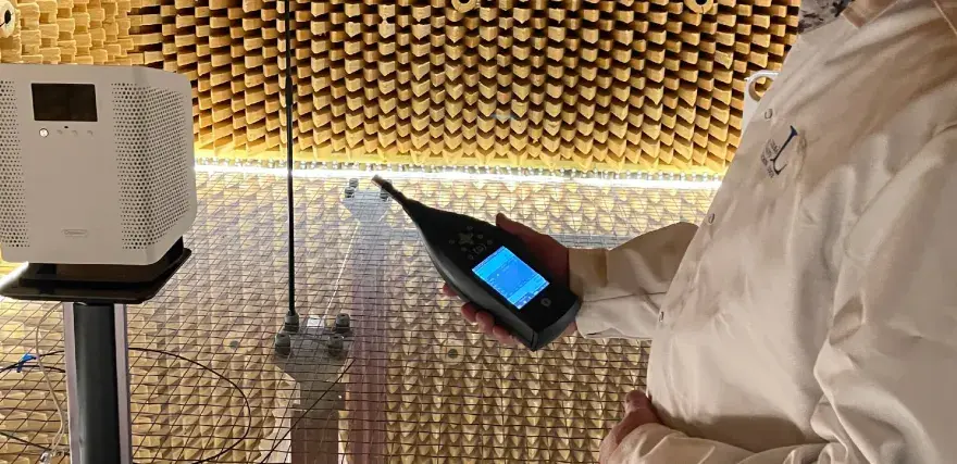 Person i laboratorierock mäter ljudnivån från en luftrenare utan filter i ett ekofritt rum.