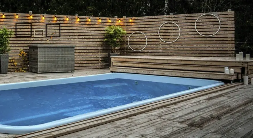 En avkopplande utomhusmiljö med pool och trädäck. En idé för att bygga eget pooltak kan inspireras av den snygga träpanelen och belysningen.
