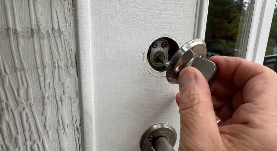 En hand håller en nyckel till ett nfc lås på en vit dörr.
