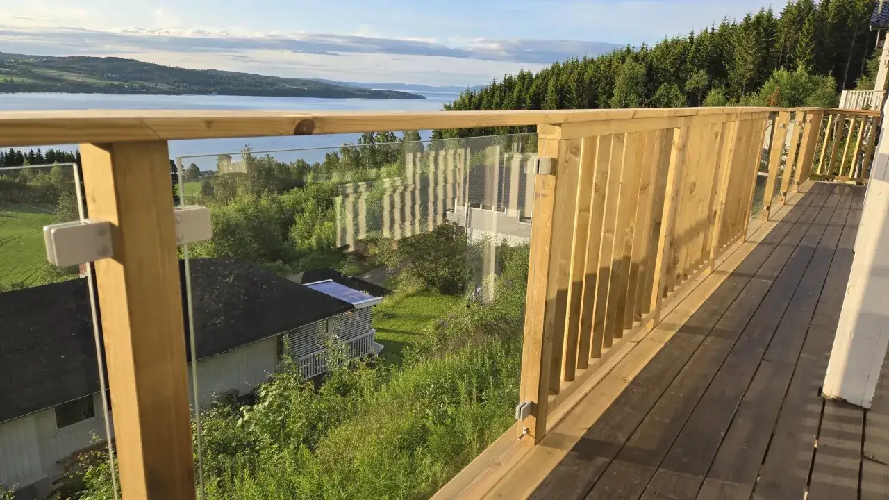 Träaltan med glaspartier ger fin altan staket inspiration. Vacker utsikt över sjö och skog.